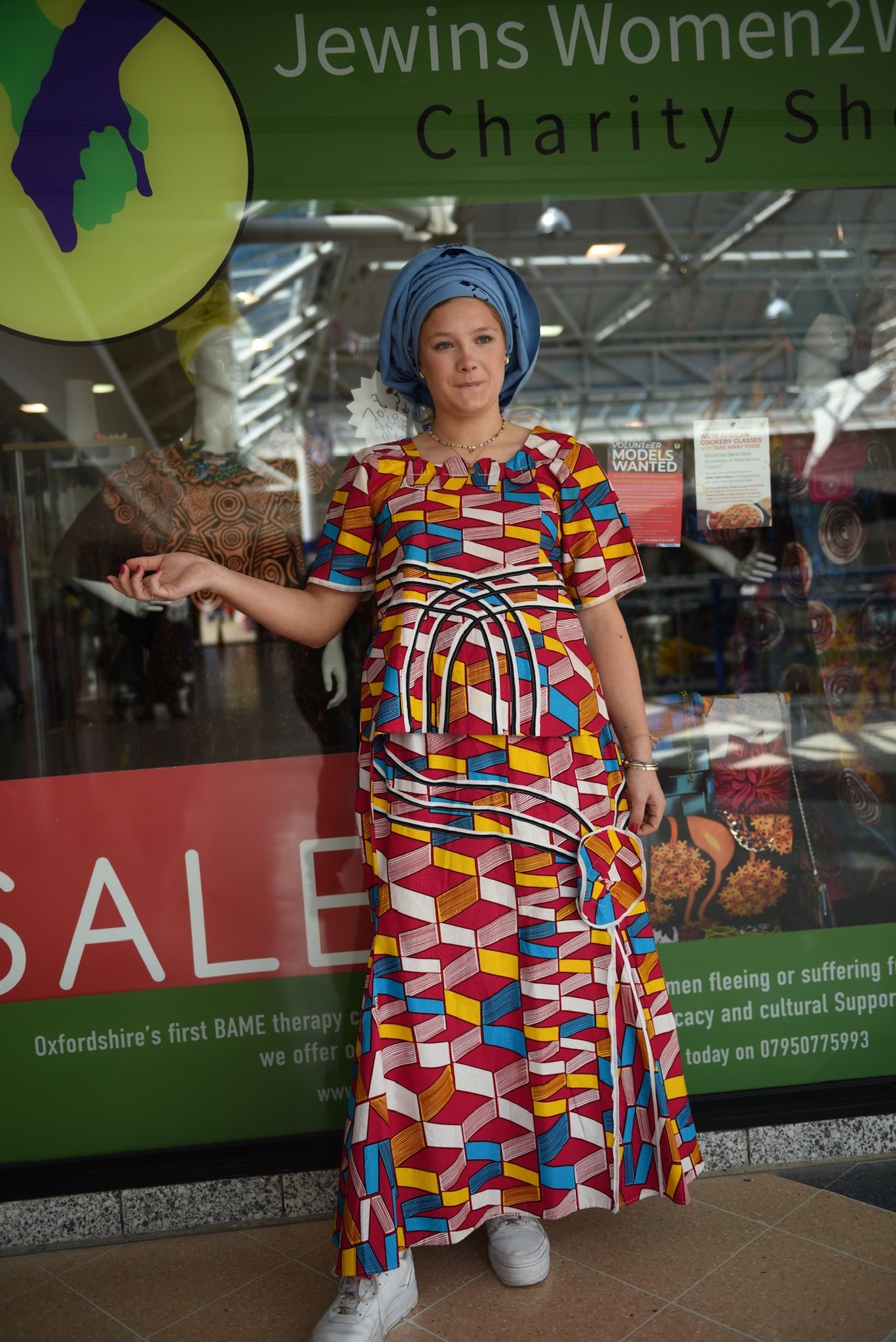 Guest in colorful traditional attire outside a charity shop
